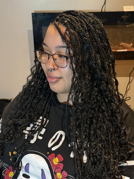 Long individual braids blending into curly ends, close-up side view